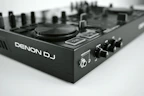 Denon DJ controller showcased on a wooden DJ booth with headphones