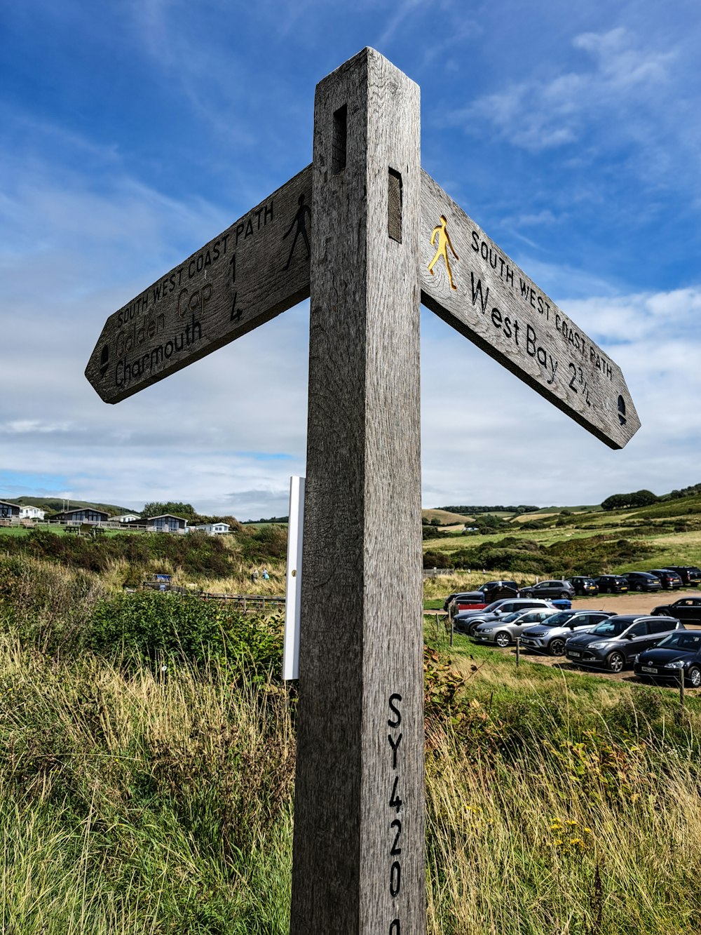 a wooden sign pointing in different directions in a parking lot