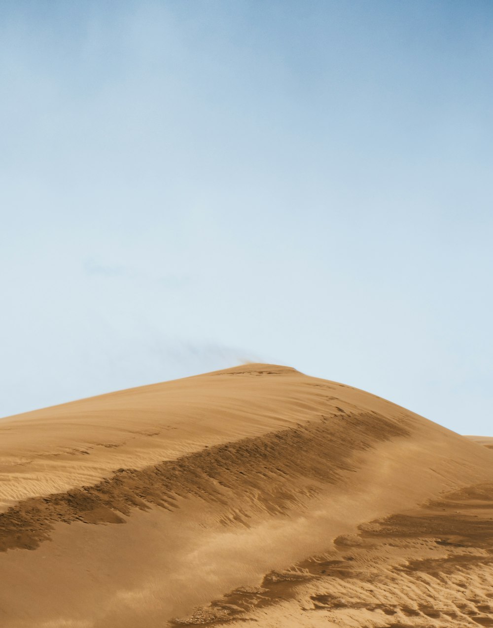 a large sand dune with a blue sky in the background