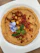 Close-up of a beautifully arranged artisanal hummus platter with vibrant colors and fresh pita bread on a rustic wooden table.