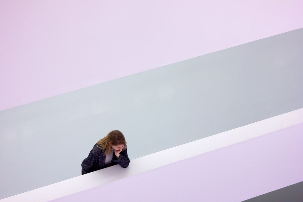 a woman leaning against a wall with her hand on her face