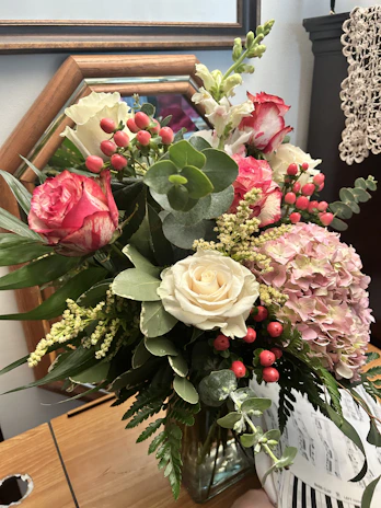 A vibrant professional floral arrangement featuring a mix of roses, alstroemeria, and gypsophila.