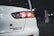 A close-up view of the rear section of a white car, highlighting the tail light. The car is in a dimly lit parking garage. The badge on the back of the car reads 'Evolution Final Edition.'
