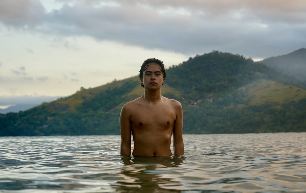 a shirtless man standing in a body of water