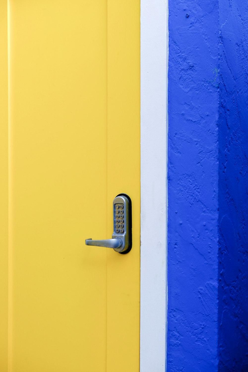 una porta gialla con un muro blu e bianco dietro di essa
