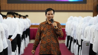 a man holding a microphone standing in front of a group of people