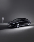 A sleek electric car charging at a modern urban station during sunset.