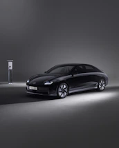 A sleek, modern office space with a glowing EV charger visible through a large window at dusk.