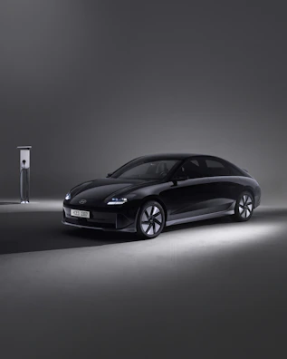 A sleek electric car charging at a modern urban station during sunset.
