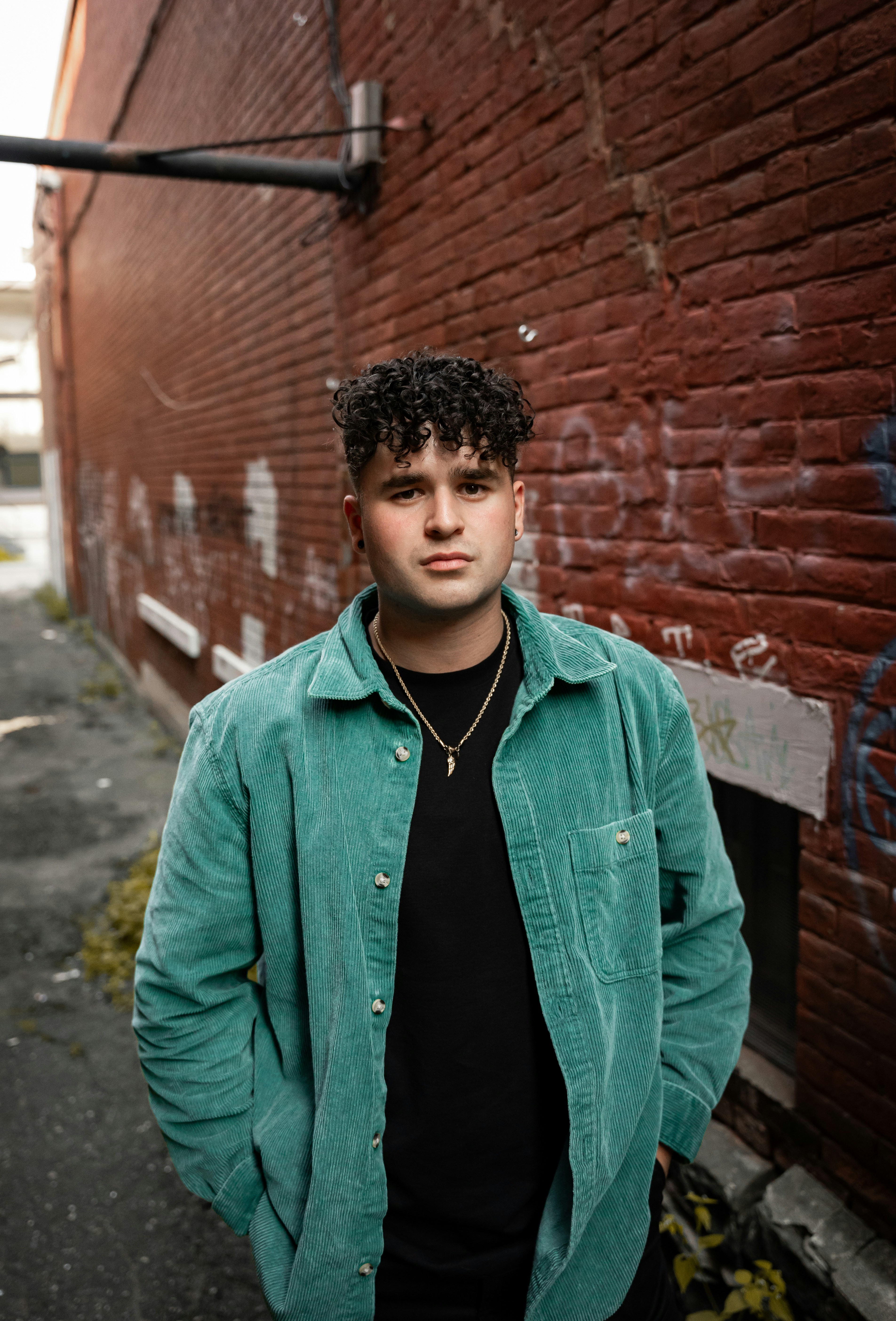 A young man standing in front of a brick wall photo – Free Boy Image on ...