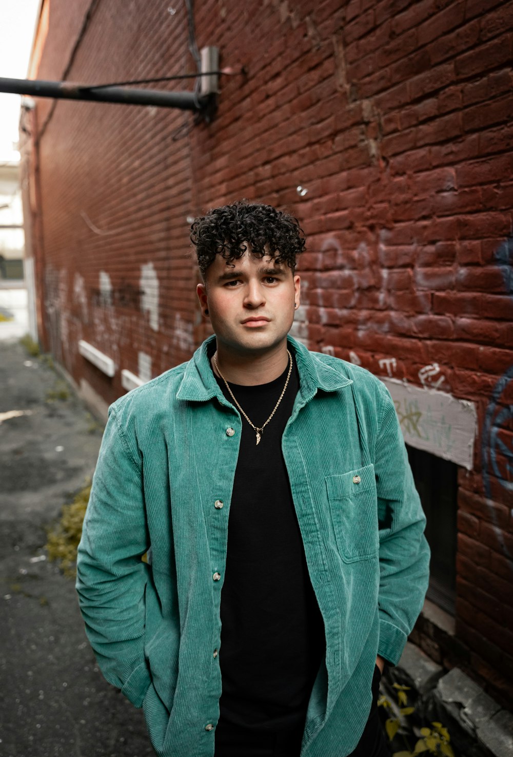 a young man standing in front of a brick wall