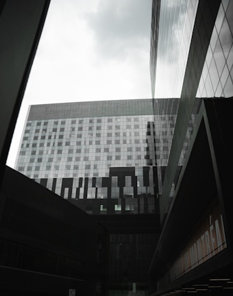 Modern office buildings with glass facades reflecting the city skyline under a cloudy sky.