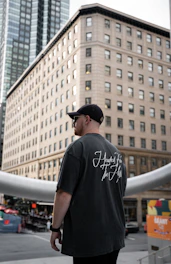 Model wearing a sleek futuristic t-shirt standing against a cityscape at dusk.
