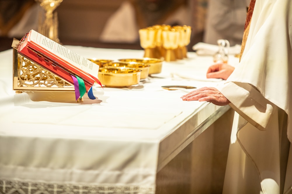 a priest standing in front of a table with a book on it