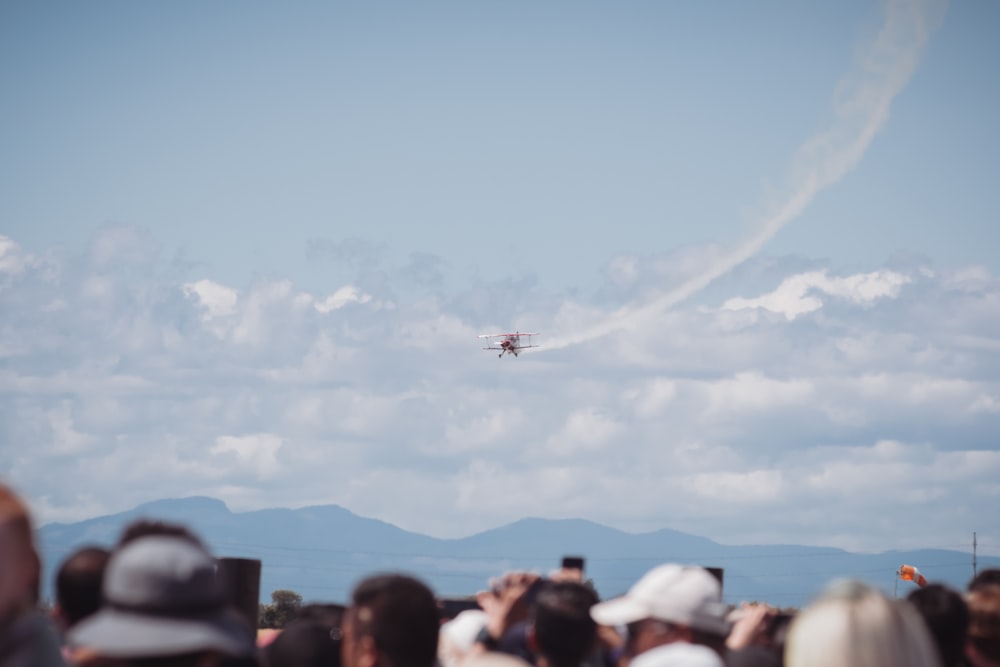 a crowd of people watching a plane fly through the air