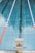 Swimming pool lane with marked starting block number three in the foreground. The pool water is clear, and there are two lane dividers, one red and one blue and white, running parallel on either side.