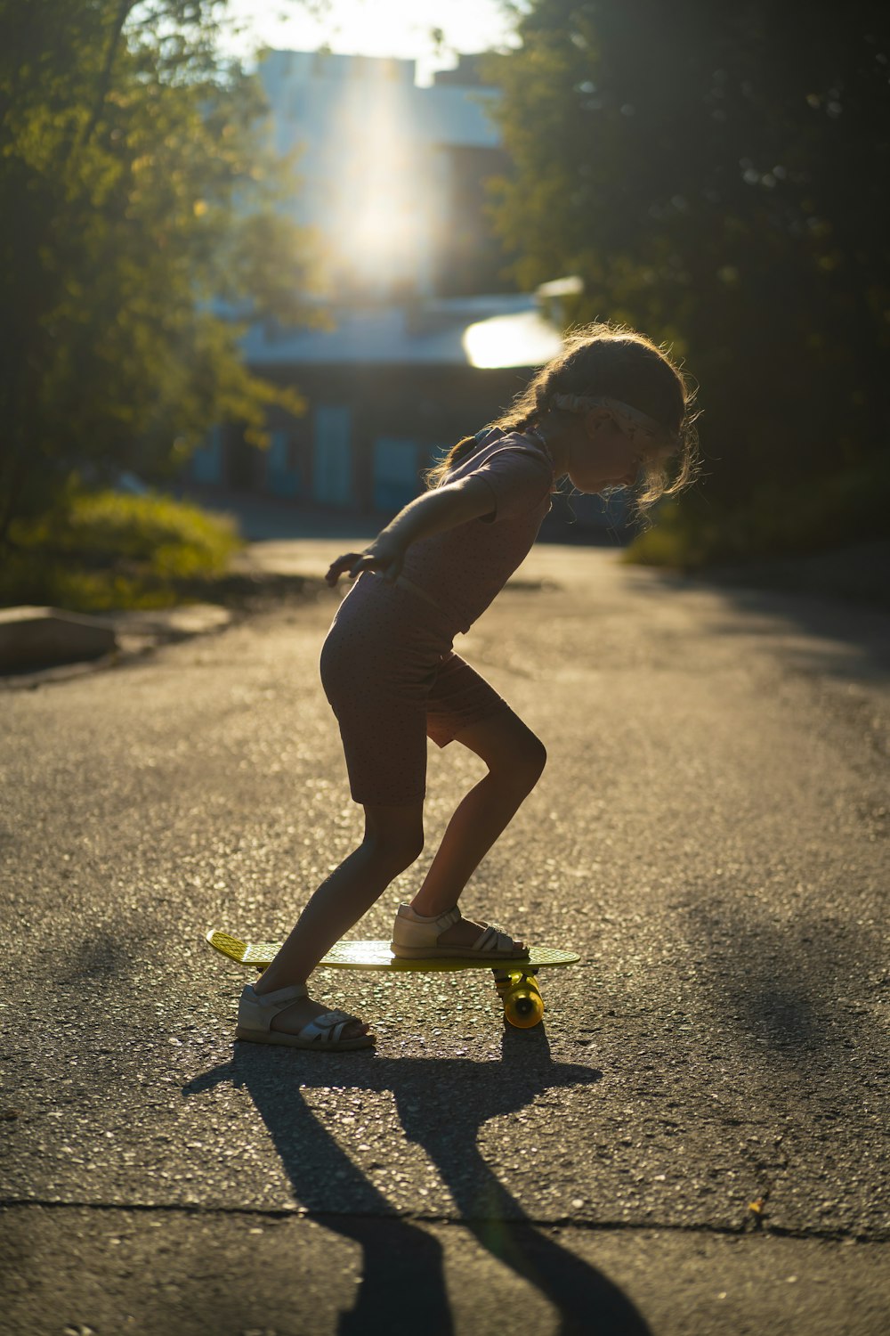 a little girl riding a skateboard down a street