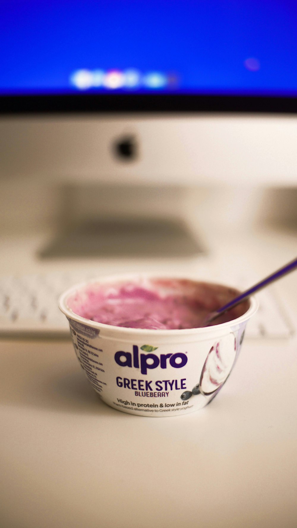 a bowl of greek style yogurt sitting in front of a computer