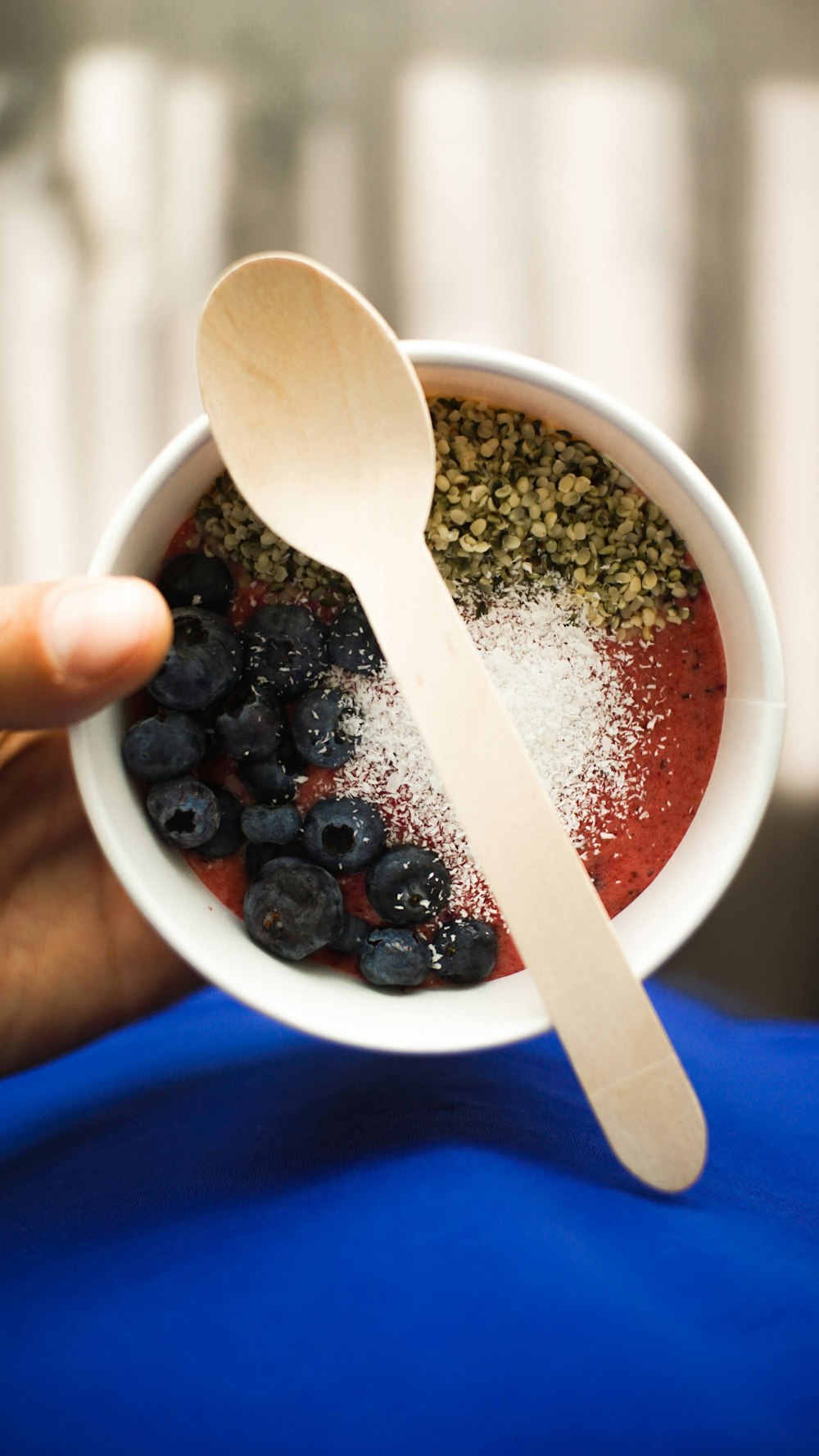 a person holding a bowl of food with a spoon