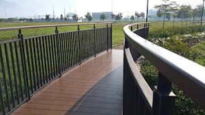 A long wooden-colored PRFV pultruded walkway winding through a green park area