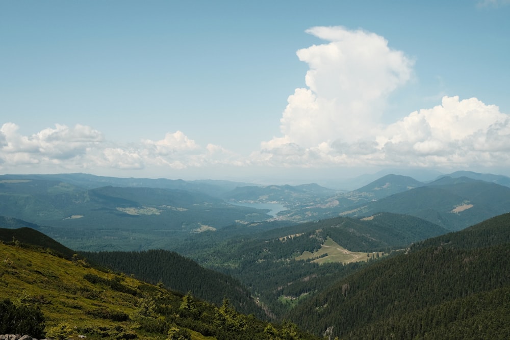 a view of a valley and mountains from the top of a hill