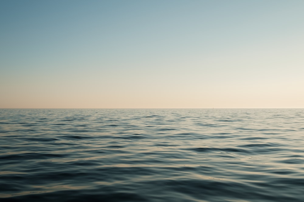 a large body of water with a sky in the background