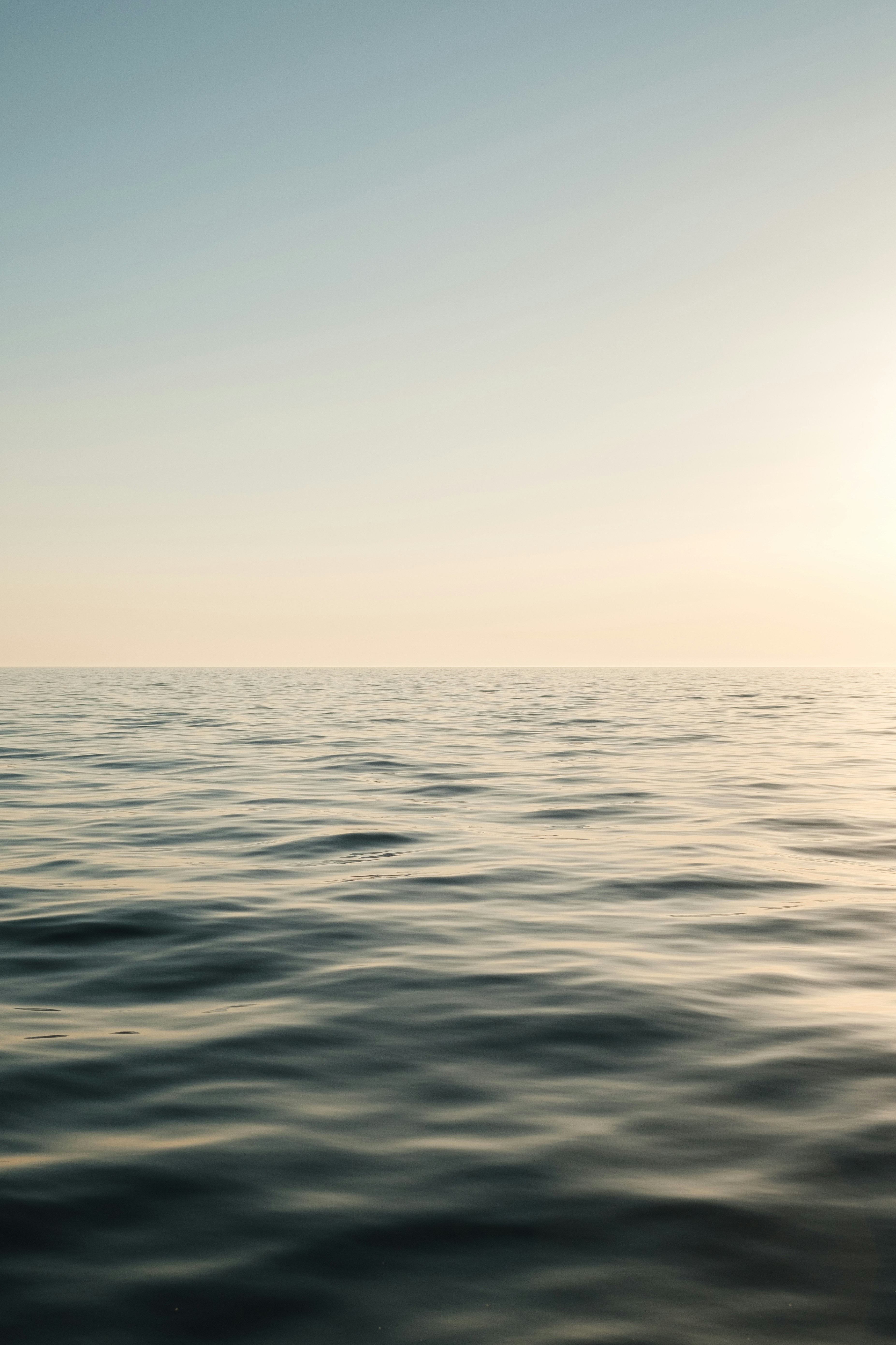 a large body of water with the sun in the distance
