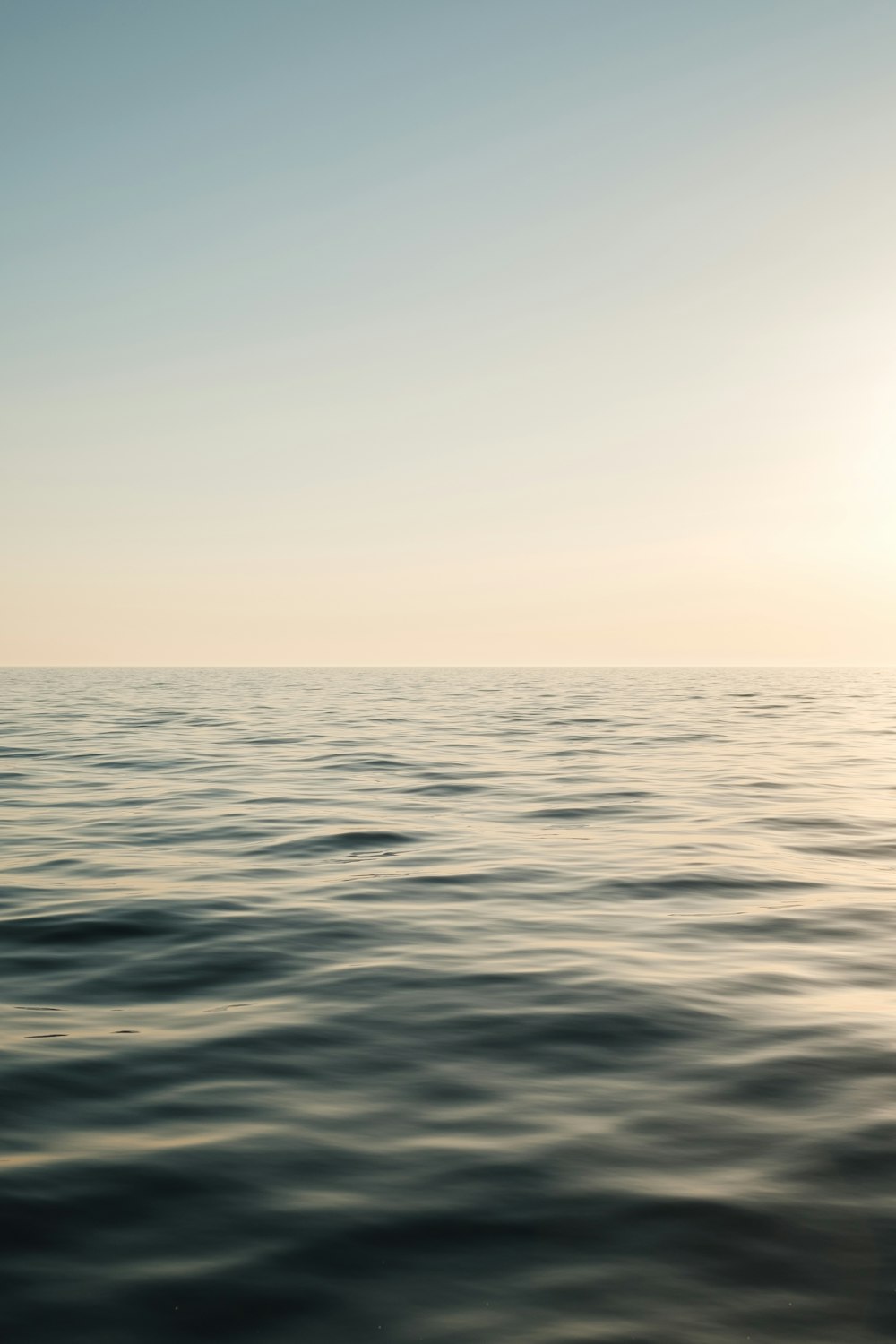 a large body of water with the sun in the distance