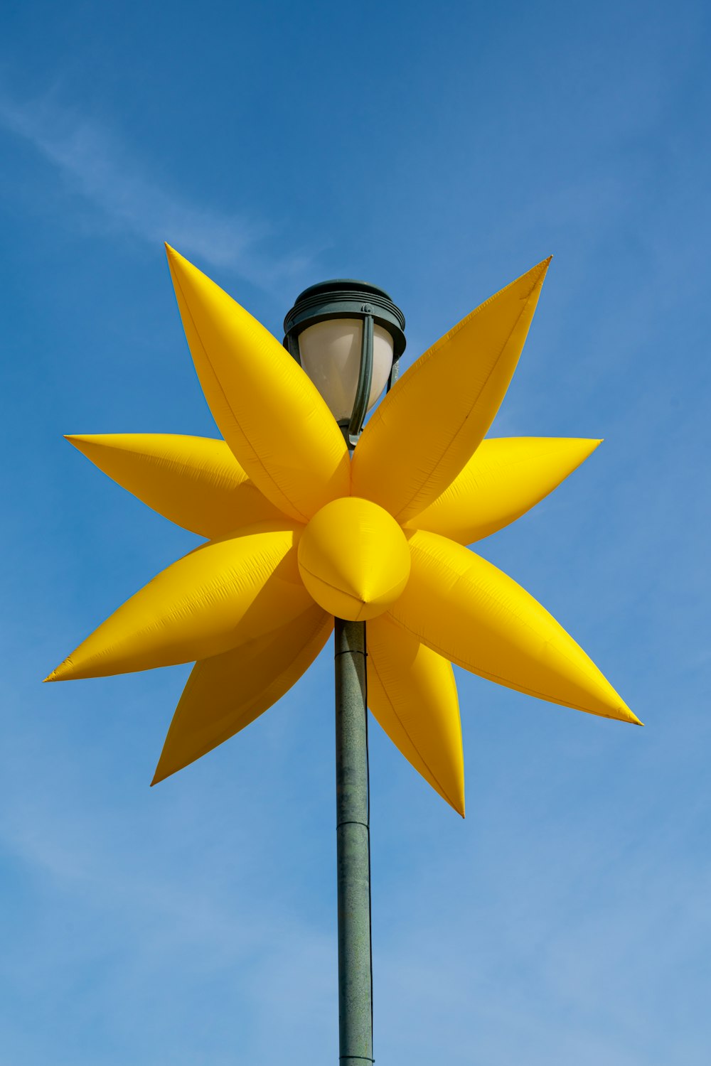 eine Straßenlaterne mit einer großen gelben Blume darauf