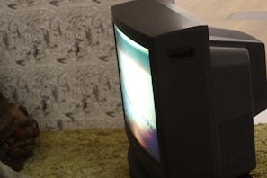 A grainy photo of a vintage CRT monitor displaying a fiery red pixelated scream.