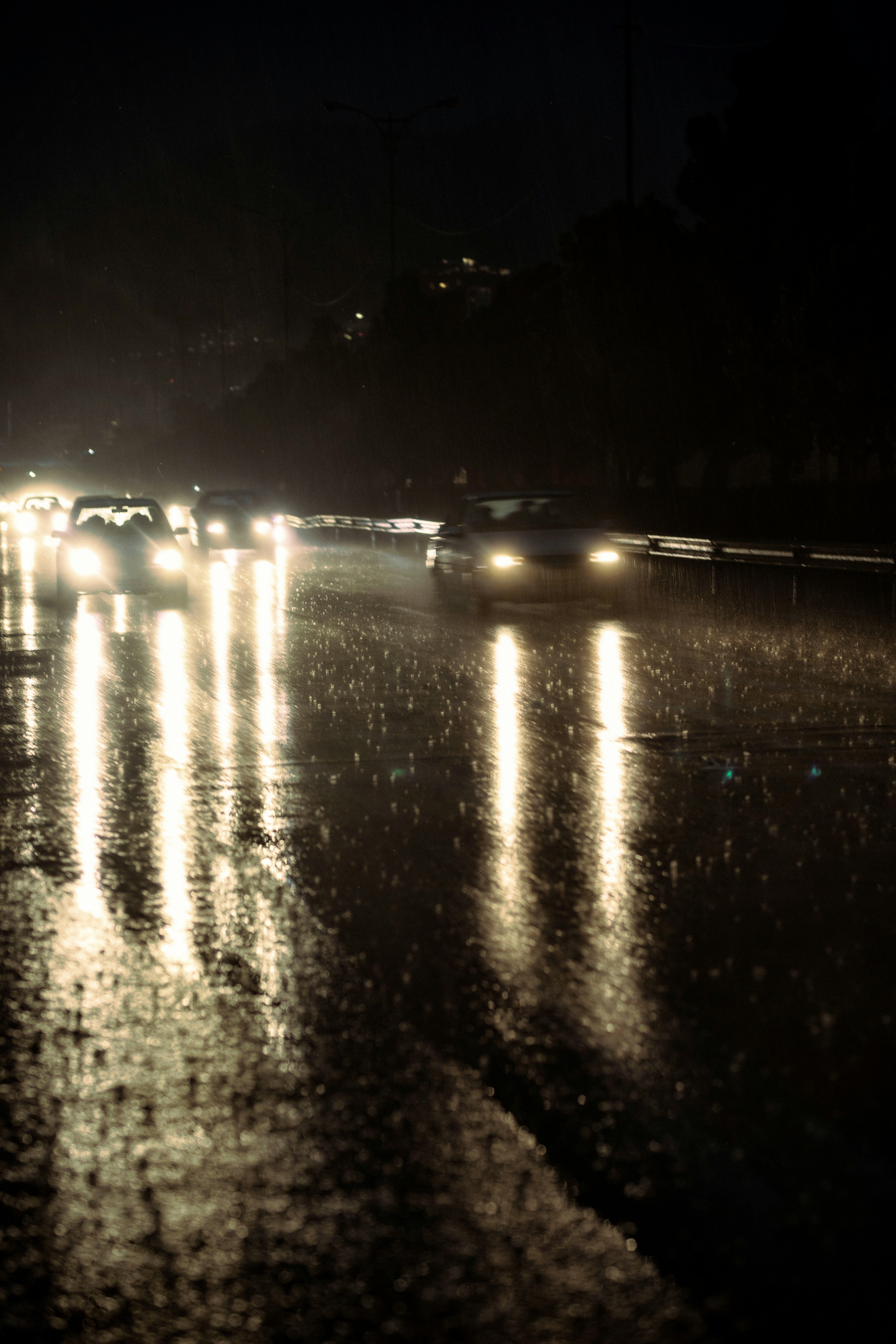 Un grupo de coches conduciendo por una calle por la noche