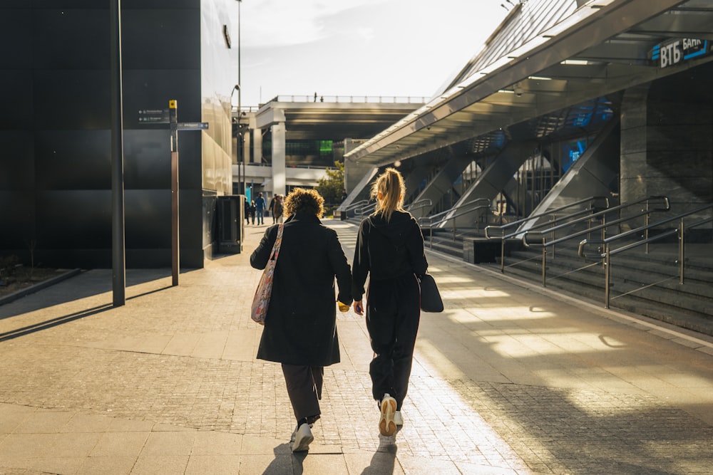 two women walking down a sidewalk holding hands