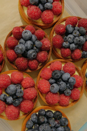 Brightly colored fruit-topped tarts arranged beautifully on a white ceramic platter
