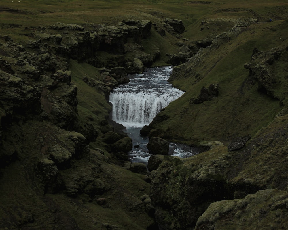 a small waterfall in the middle of a grassy area