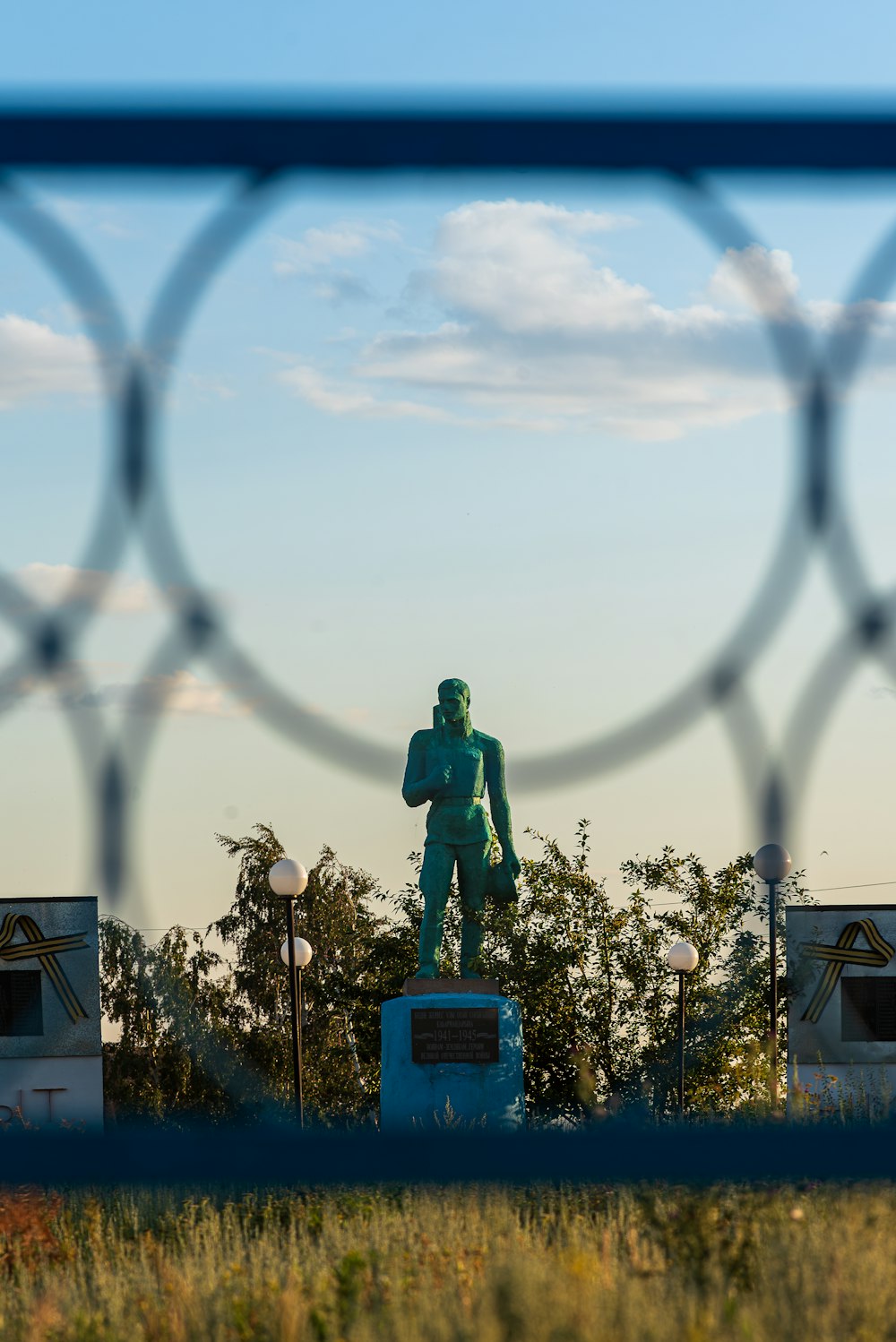 a statue of a man is seen through a fence
