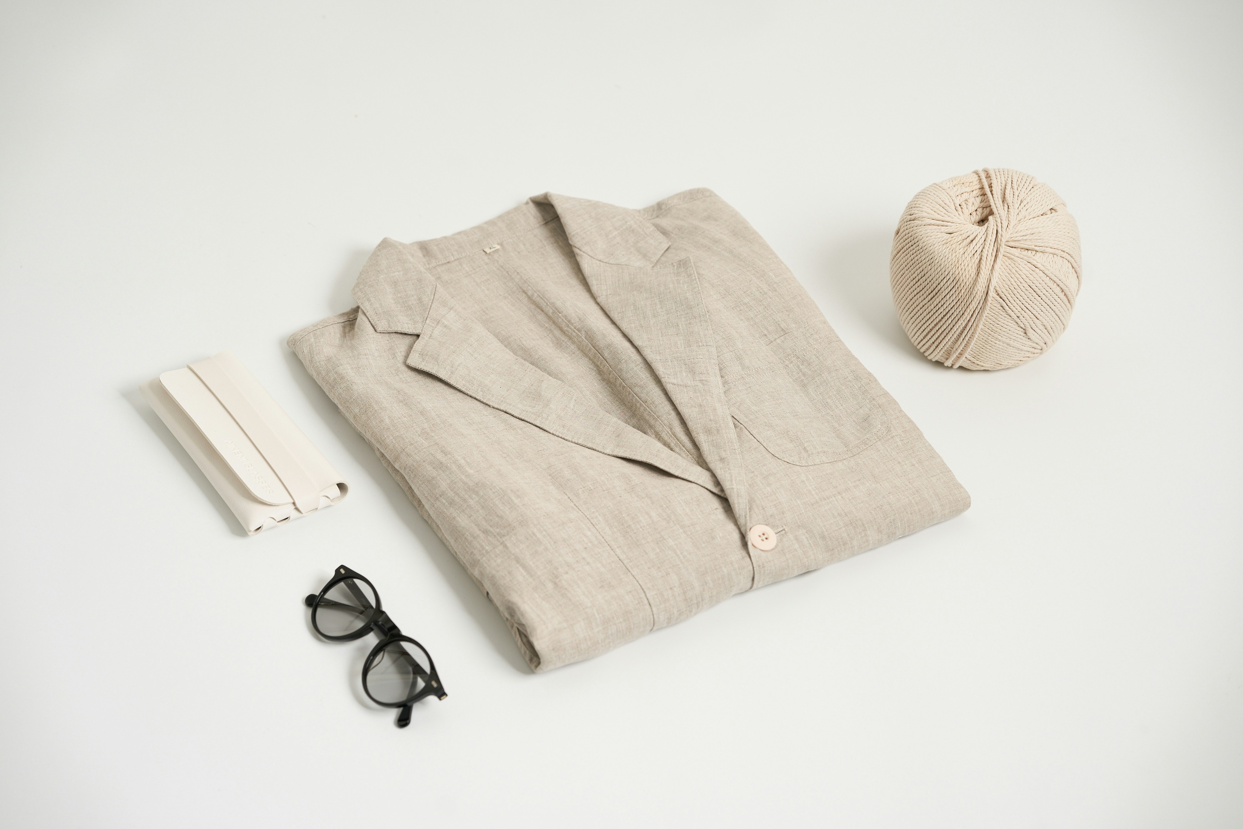 a pair of glasses, a ball of yarn, a pair of sunglasses, and, A linen suit placed on the table