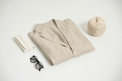 Une veste en lin beige pliée, avec des lunettes et une pelote de ficelle