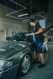 A sleek car being carefully cleaned by a professional in a bright, modern garage.
