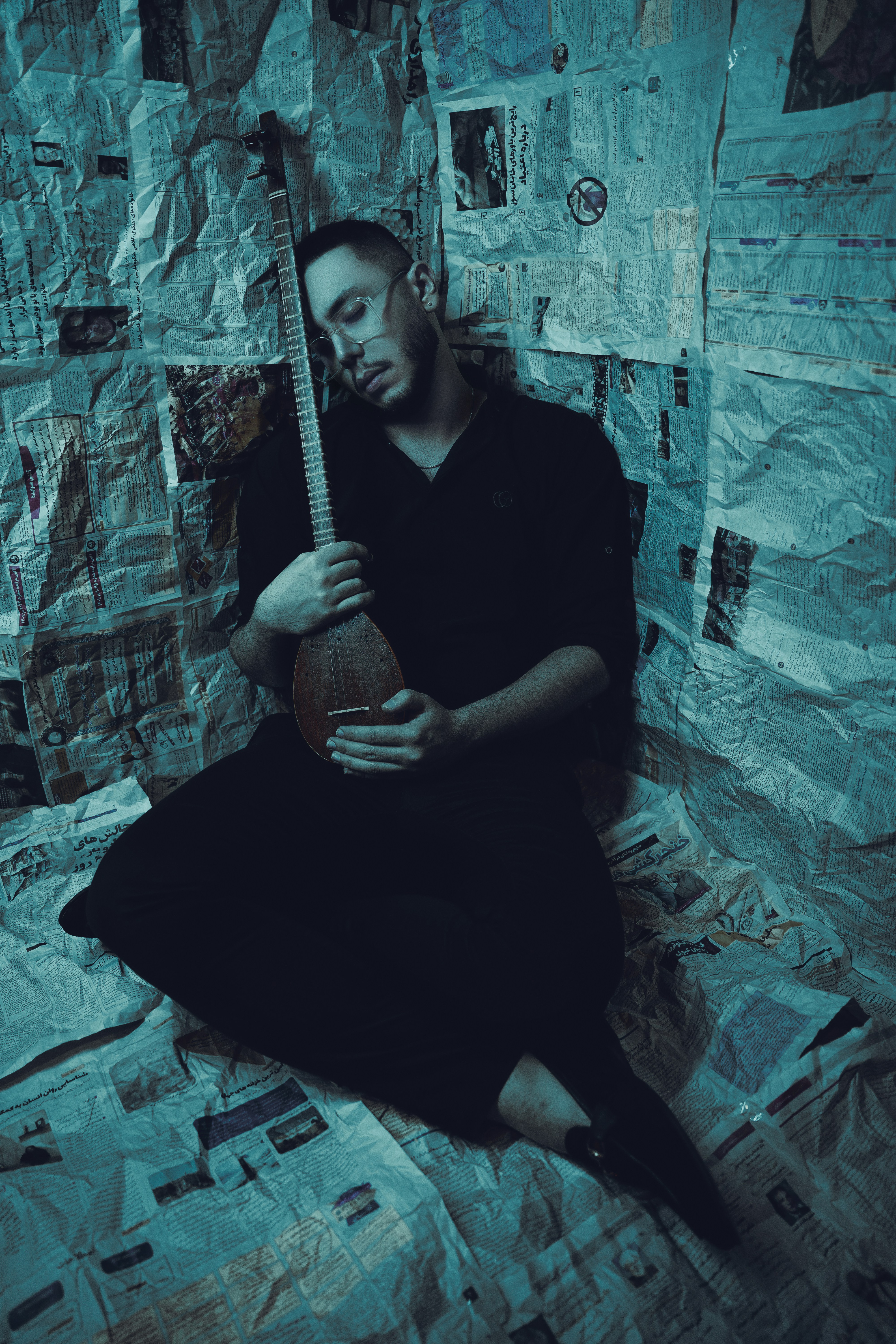 Un uomo seduto sopra un letto che tiene una chitarra