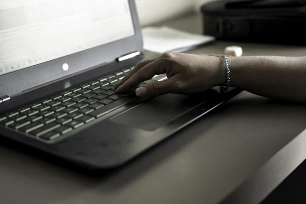 Close-up of hands typing on a laptop keyboard with a black and gold Onyx Digital Flow branded notebook nearby.