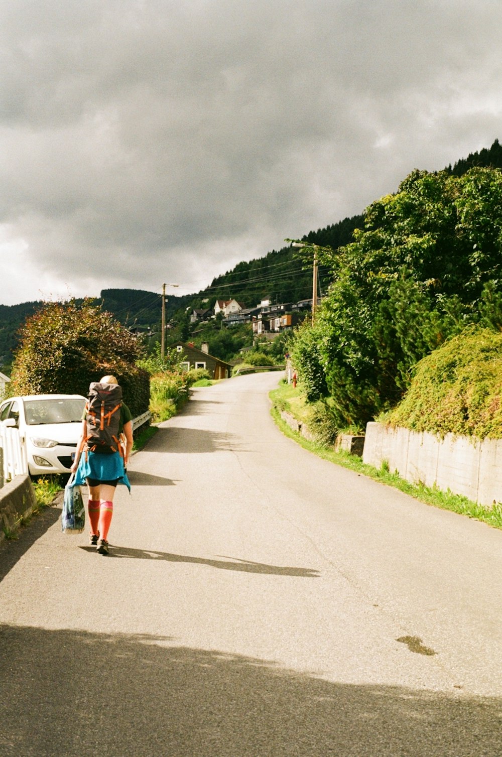 a woman walking down a road carrying a suitcase