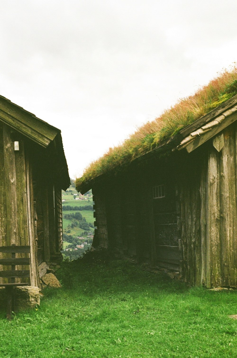 a couple of wooden buildings sitting on top of a lush green field