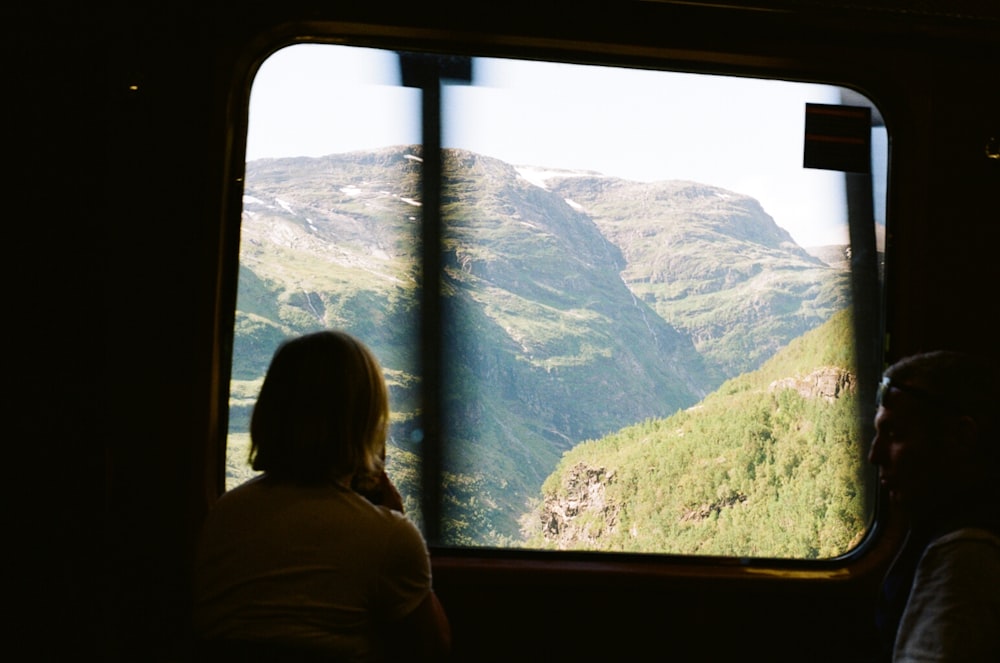 a person looking out a window at a mountain