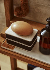 Bottles of liquid soaps with natural ingredients and subtle floral labels arranged on a bathroom shelf.
