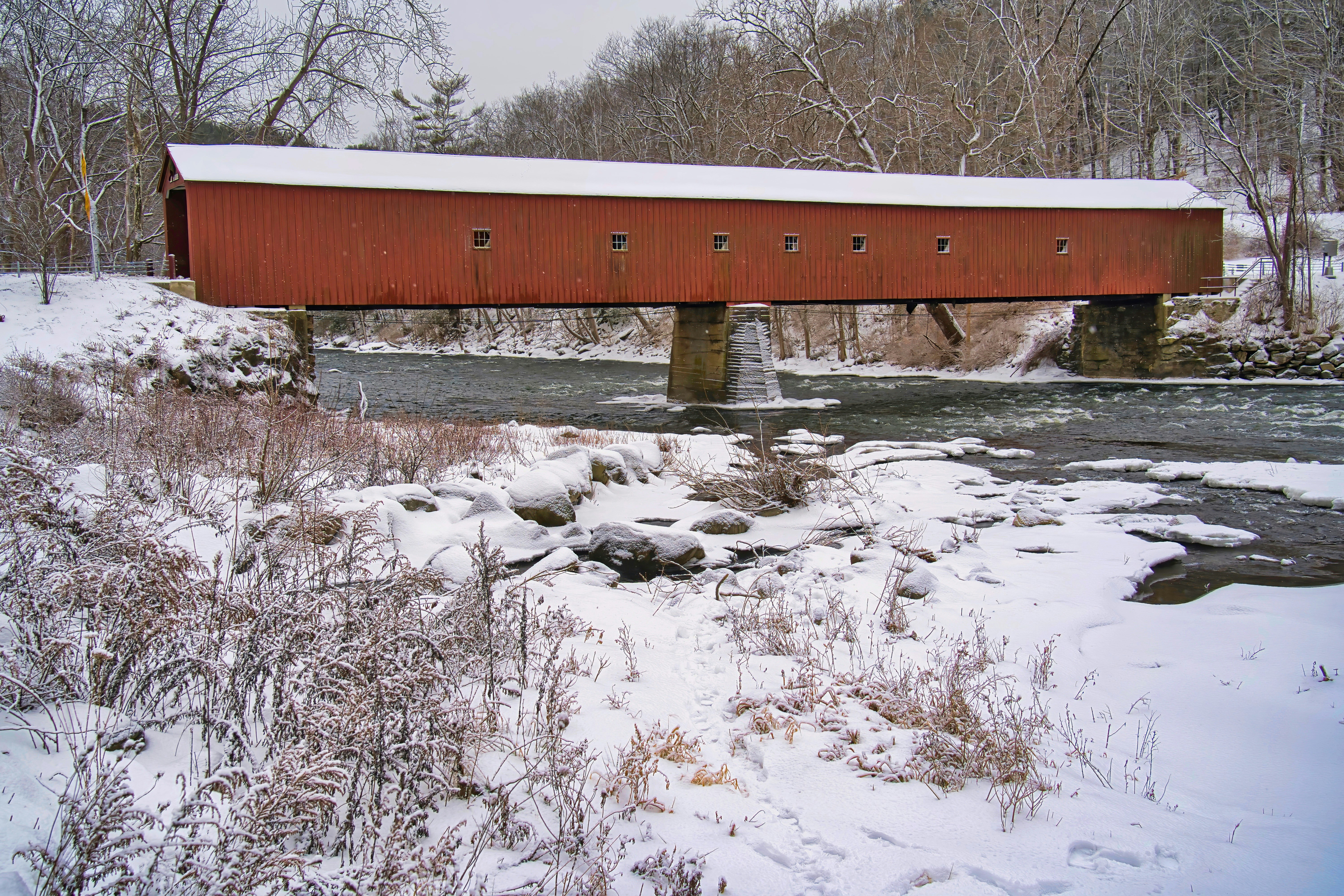a red covered bridge over a small stream
