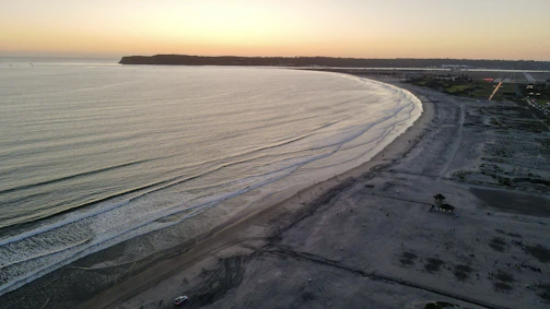Aerial view of Garopaba coastline at sunset with calm waves and sandy beaches.