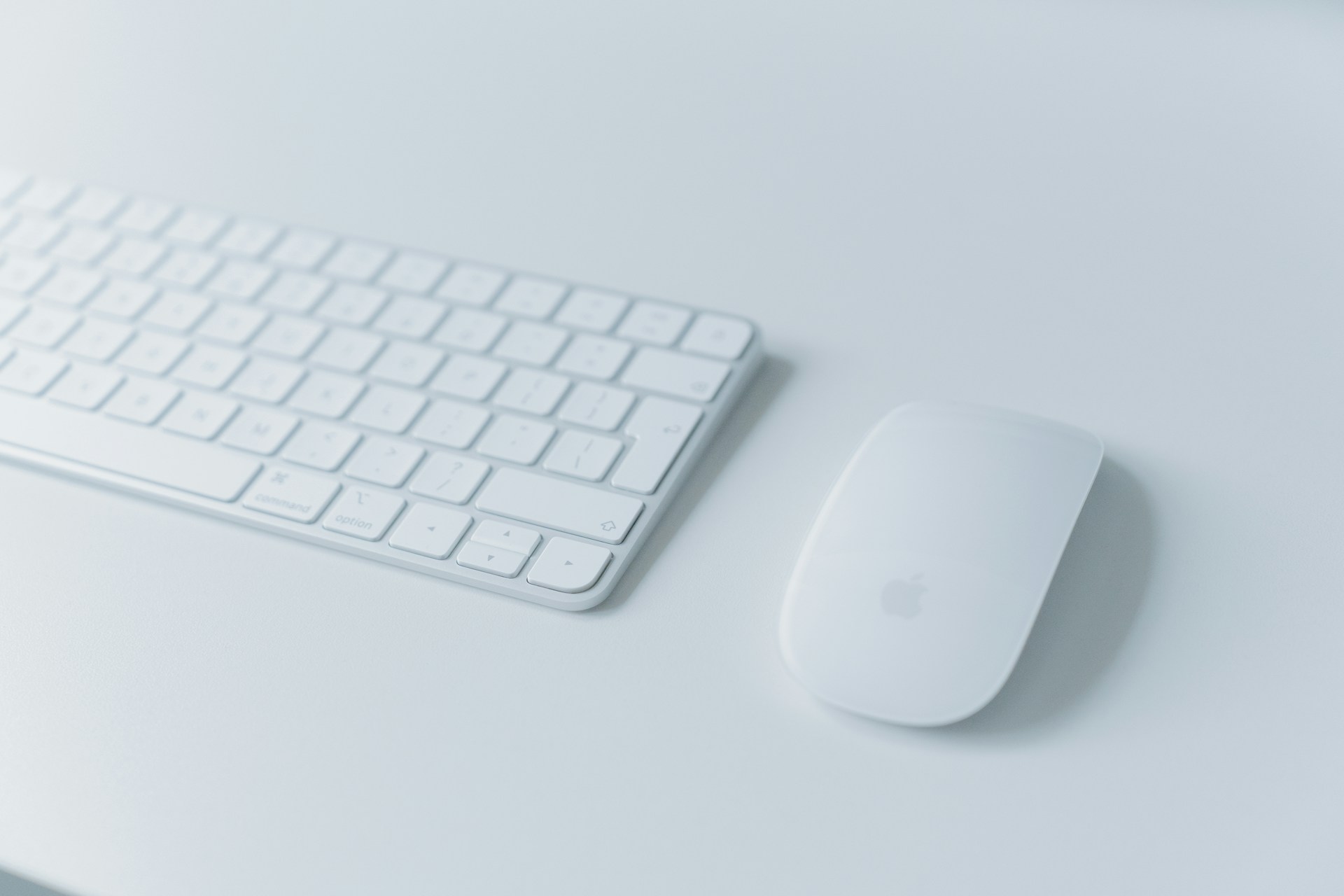 a computer keyboard and mouse on a white desk