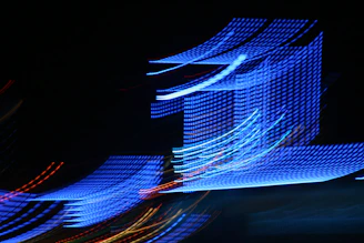 A dark, cinematic scene featuring dynamic neon blue and red light trails weaving through abstract shapes.