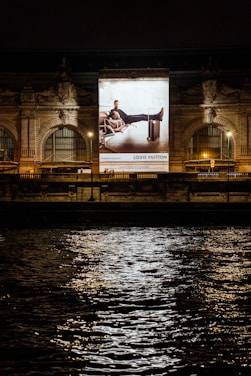 illuminated ad for a luxury brand shining on an ornate building at night