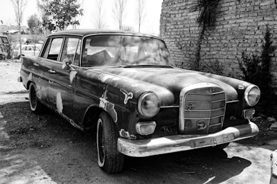A rusty old car parked beside a Bronx street, ready for donation.